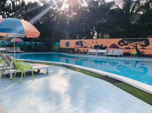 a swimming pool with a table and an umbrella at Tea Heaven Resort in Sreemangal