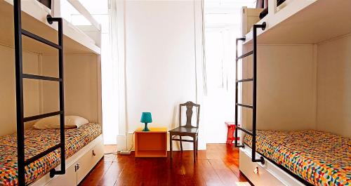 a bedroom with two bunk beds and a chair at Aveiro Rossio Hostel in Aveiro