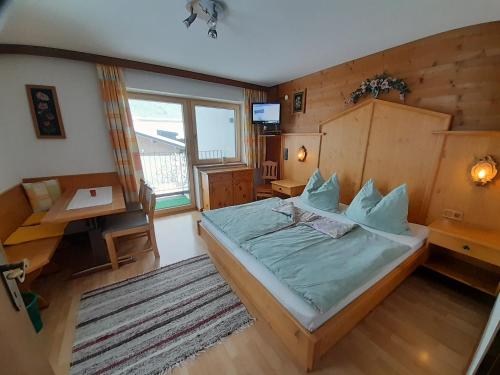 um quarto com uma cama, uma mesa e uma janela em Haus Rosenegg em Brixen im Thale