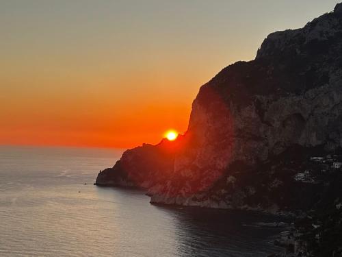 einen Sonnenuntergang über dem Meer mit einer Klippe in der Unterkunft Roberhouse Tragara 37 in Capri