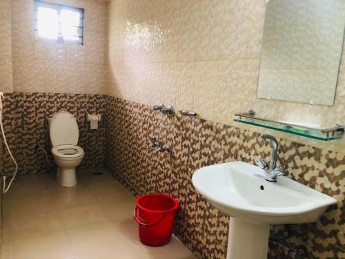 a bathroom with a sink and a toilet and a mirror at Tea Heaven Resort in Sreemangal