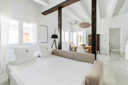 a white bedroom with a large bed and a table at El Erizo Apartamentos in Tarifa