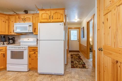 a white refrigerator in a kitchen with wooden cabinets at Henrys Post by KABINO Dog Friendly Foosball Fire Pit SmartTV WiFi in Island Park