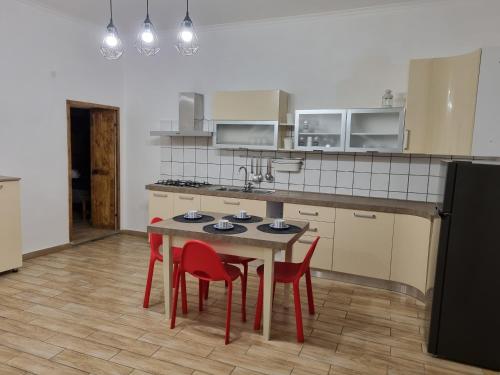 uma cozinha com uma mesa e quatro cadeiras vermelhas em O' Palazziell em Nápoles