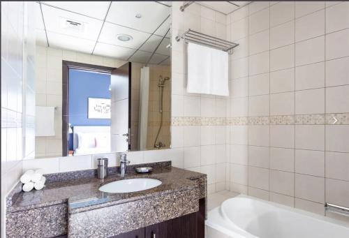 een badkamer met een wastafel, een bad en een tubermott bij شقق فندقية in Dubai