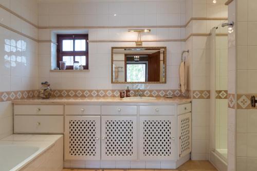 a bathroom with a sink and a mirror and a tub at Akisol Faro Relax in Faro