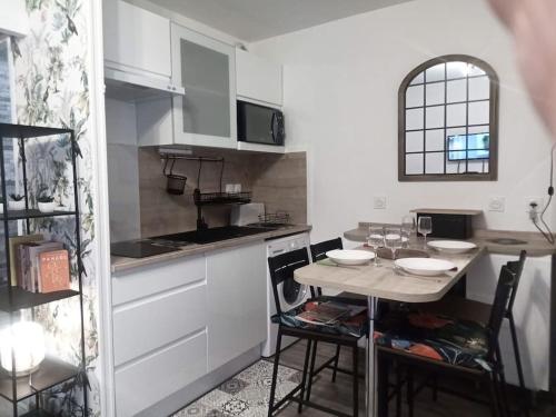 une cuisine avec une table, des chaises et un comptoir dans l'établissement joli appartement T2 très bien situé, parking couvert, à Lourdes