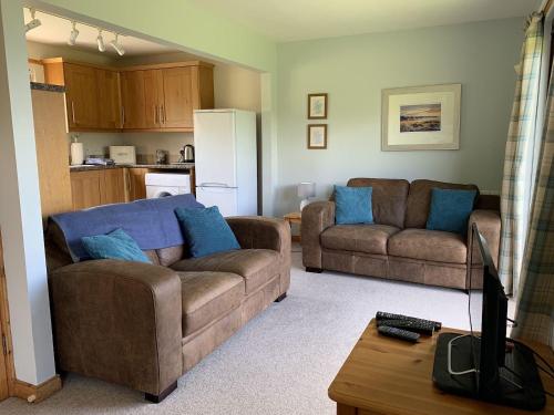 a living room with two couches and a kitchen at Thistle Cottage in Lairg