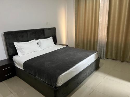 Schlafzimmer mit einem großen Bett mit einem schwarzen Kopfteil in der Unterkunft Nuben Court-Accra in Accra
