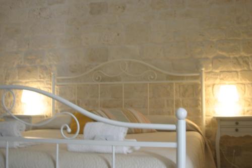 a bedroom with a white bed and a stone wall at B&B Fiano Marchione in Castellana Grotte