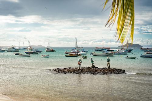 three men standing on a small island in the water with boats at Suri Búzios Hotel in Búzios