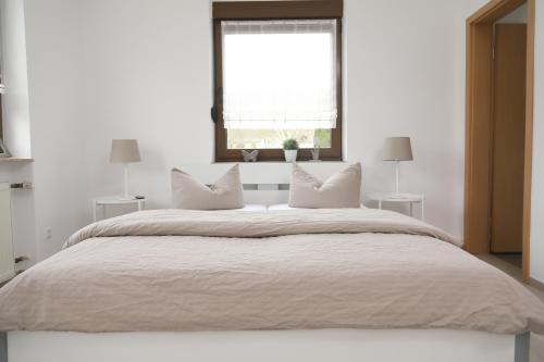 a white bedroom with a large bed with a window at Pension Gästehaus La Mula in Treis-Karden