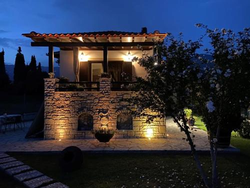 a stone building with a porch at night at ZENIA Pelion garden house in Platanidia