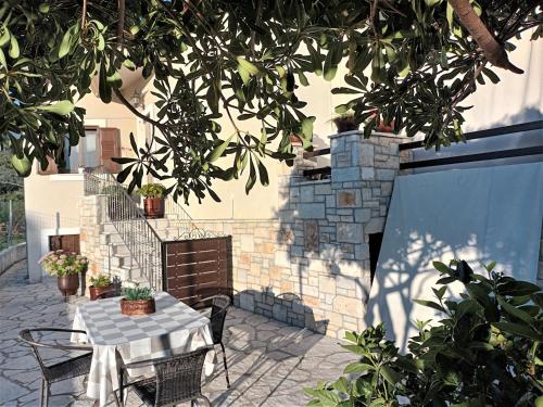 a patio with a table and chairs under a tree at ZENIA Pelion garden house in Platanidia