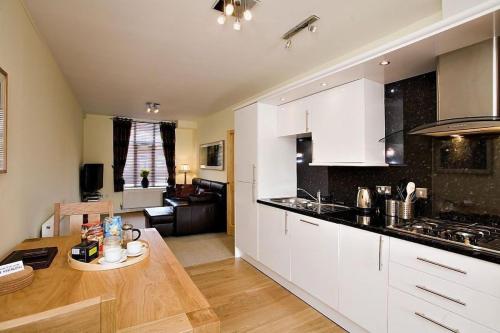 a kitchen with white cabinets and a table in a room at Croft Mill in Hebden Bridge
