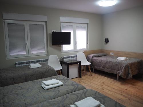 a room with two beds and a flat screen tv at Hostal Acella in Pamplona