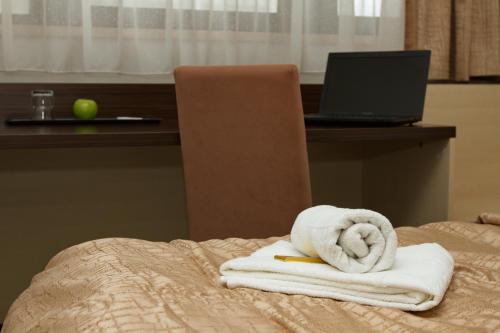 uma pilha de toalhas numa cama com um computador portátil em Hotel Expo em Bratislava