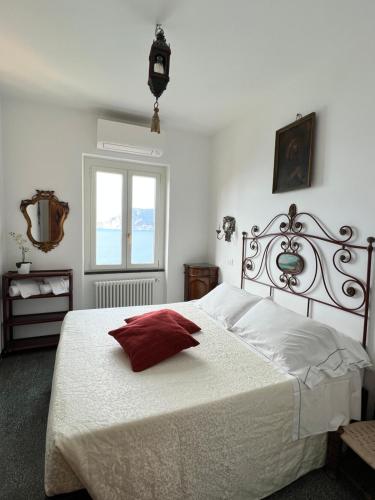 a bedroom with a white bed with a red pillow at Il Conventino delle Cinque Terre - Sea View - AC&WiFi - Vernazzarentals in Vernazza