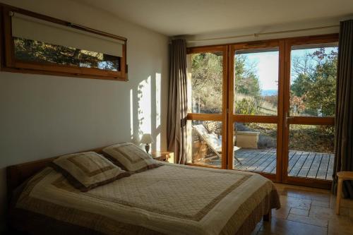 um quarto com uma cama e uma grande janela em La Source em Saint-Saturnin-dʼApt