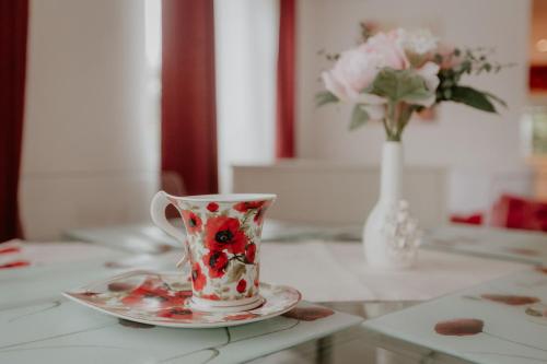 a red and white coffee cup on a table with a vase at Cannock Chase Guest House Self Catering incl all home amenities & private entrance in Cannock