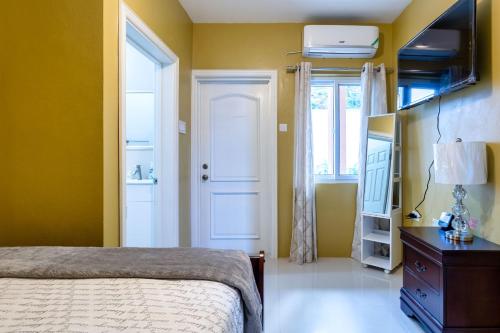 a bedroom with yellow walls and a bed and a door at BayWatch Villa - Montego Bay in Montego Bay