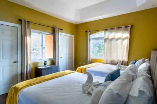 two beds in a bedroom with yellow walls and windows at BayWatch Villa - Montego Bay in Montego Bay