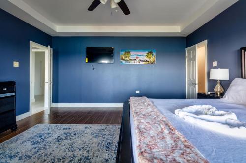 a blue bedroom with a bed and a flat screen tv at BayWatch Villa - Montego Bay in Montego Bay