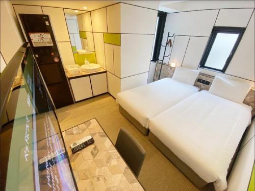 a small room with a bed and a table in it at Henn na Hotel Osaka Shinsaibashi in Osaka