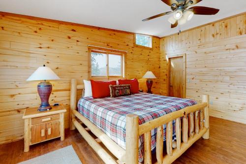 a log cabin bedroom with a bed and a ceiling fan at Rio Grande Lodge in South Fork