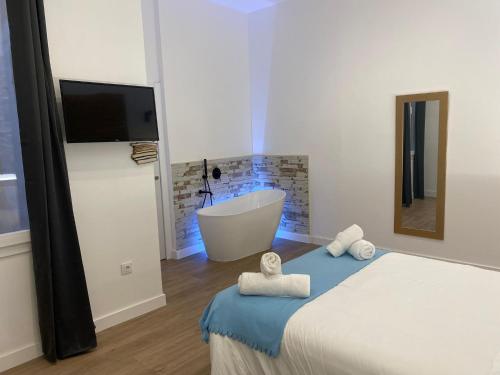 1 dormitorio con bañera y 1 cama con toallas en Sevilla deluxe suites, en Sevilla