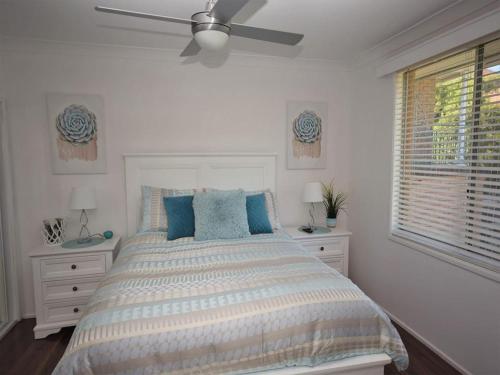 a white bedroom with a bed and a ceiling fan at Riverwood in Nambucca Heads