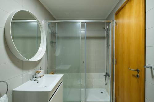 a bathroom with a shower and a sink and a mirror at Mar Grande Apartment in Ribeira Grande