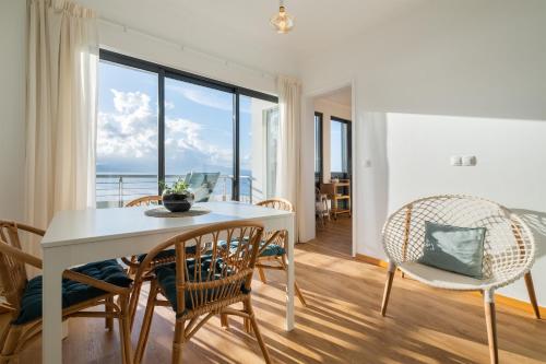 a dining room with a table and chairs and a large window at Mar Grande Apartment in Ribeira Grande