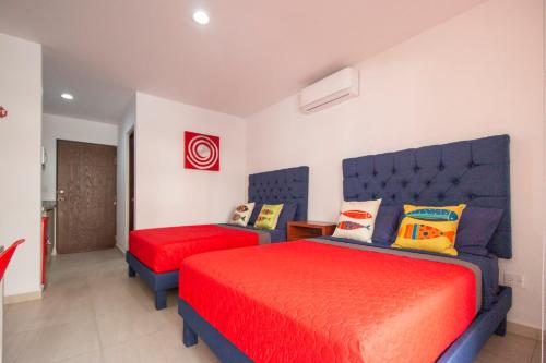 a bedroom with two beds with red and orange sheets at Ambar Condominios Mazatlan in Mazatlán