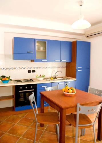 a kitchen with blue cabinets and a table with a bowl of fruit at Le Tartarughe Aparthotel in Letojanni