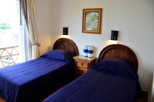 two beds with blue sheets in a room with a window at Las Palmas - Palma Xiat & Cocoyol in Playa del Carmen
