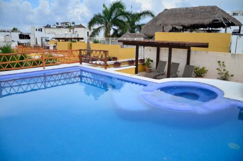 a swimming pool with blue water in front of a building at Las Palmas - Palma Xiat & Cocoyol in Playa del Carmen