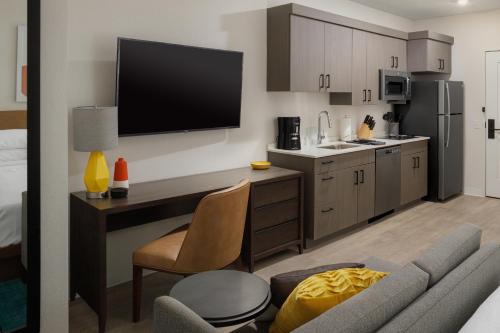 a kitchen with a desk and a tv on the wall at WaterWalk Extended Stay by Wyndham Phoenix N Happy Valley in Phoenix