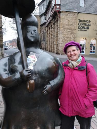 a woman is standing in front of a statue at Frauenpension Arleta - Women only in Goslar