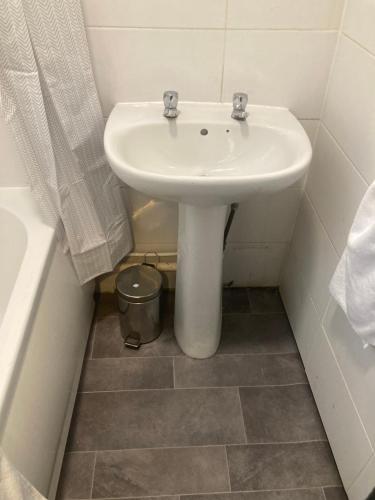 a bathroom with a white sink and a bucket at Lovely 2 Bed Sea Front apartment @ 10A George Street in Ryde
