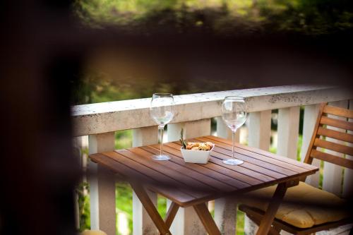 een houten tafel met twee wijnglazen en een fruitschaal bij White house in the forest in Pučišća