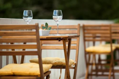 two glasses of wine sitting on a table with chairs at White house in the forest in Pučišća