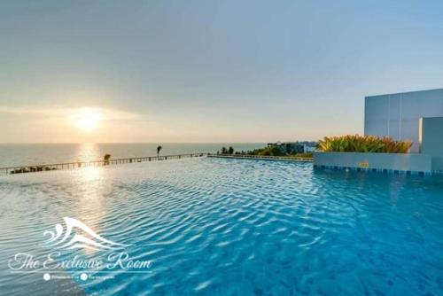 a large swimming pool with the ocean in the background at Fluffy bed and seaview @Bangsaen in Bangsaen