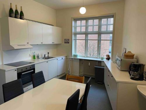 a kitchen with white cabinets and a table with chairs at Cozy 4-Bedroom Apartment Aalborg in Aalborg