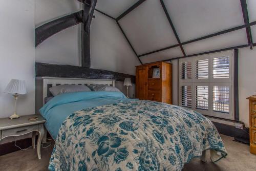 Schlafzimmer mit einem Bett mit einer blauen und weißen Bettdecke in der Unterkunft Modern living, Charming Old Town Cottage in Hastings