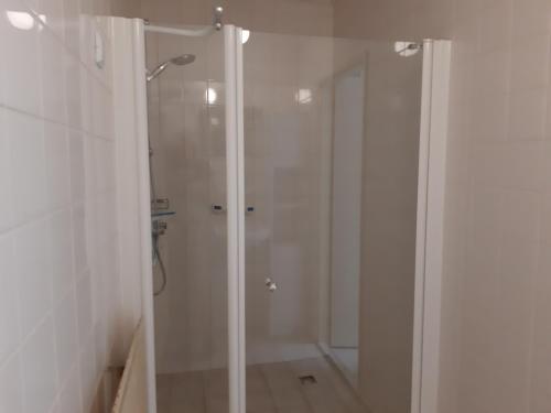 een douche met een glazen deur in de badkamer bij de Grutto in Appelscha