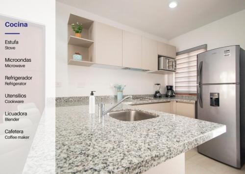 a kitchen with a sink and a stainless steel refrigerator at Ambar Condominios Mazatlan in Mazatlán