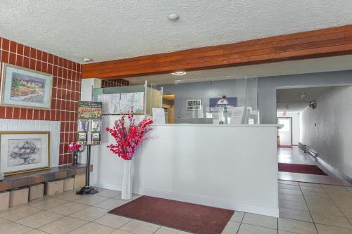 a lobby with a counter with a vase of flowers at Canadas Best Value Inn Kelowna in Kelowna