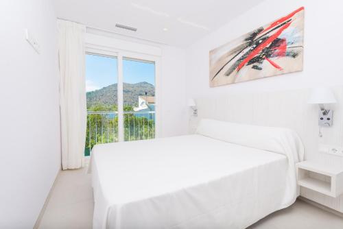 ein weißes Schlafzimmer mit einem Bett und einem Fenster in der Unterkunft NEW! Villa Lago B, Alcudia Beach, Mallorca in Port d'Alcúdia