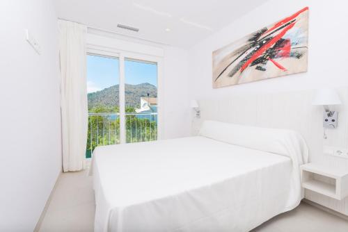 ein weißes Schlafzimmer mit einem Bett und einem Fenster in der Unterkunft NEW! Villa del Lago 2, Alcudia Beach, Mallorca in Port d'Alcúdia
